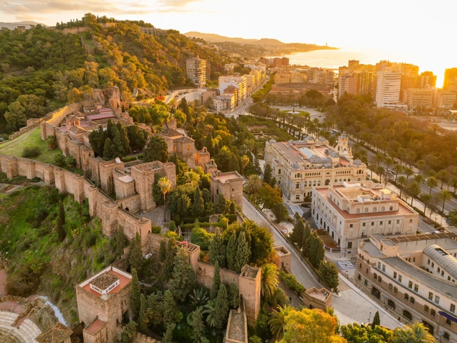 Flygfoto över Alcazaba-fästningen i Málaga med utsikt över staden och bukten vid solnedgången.