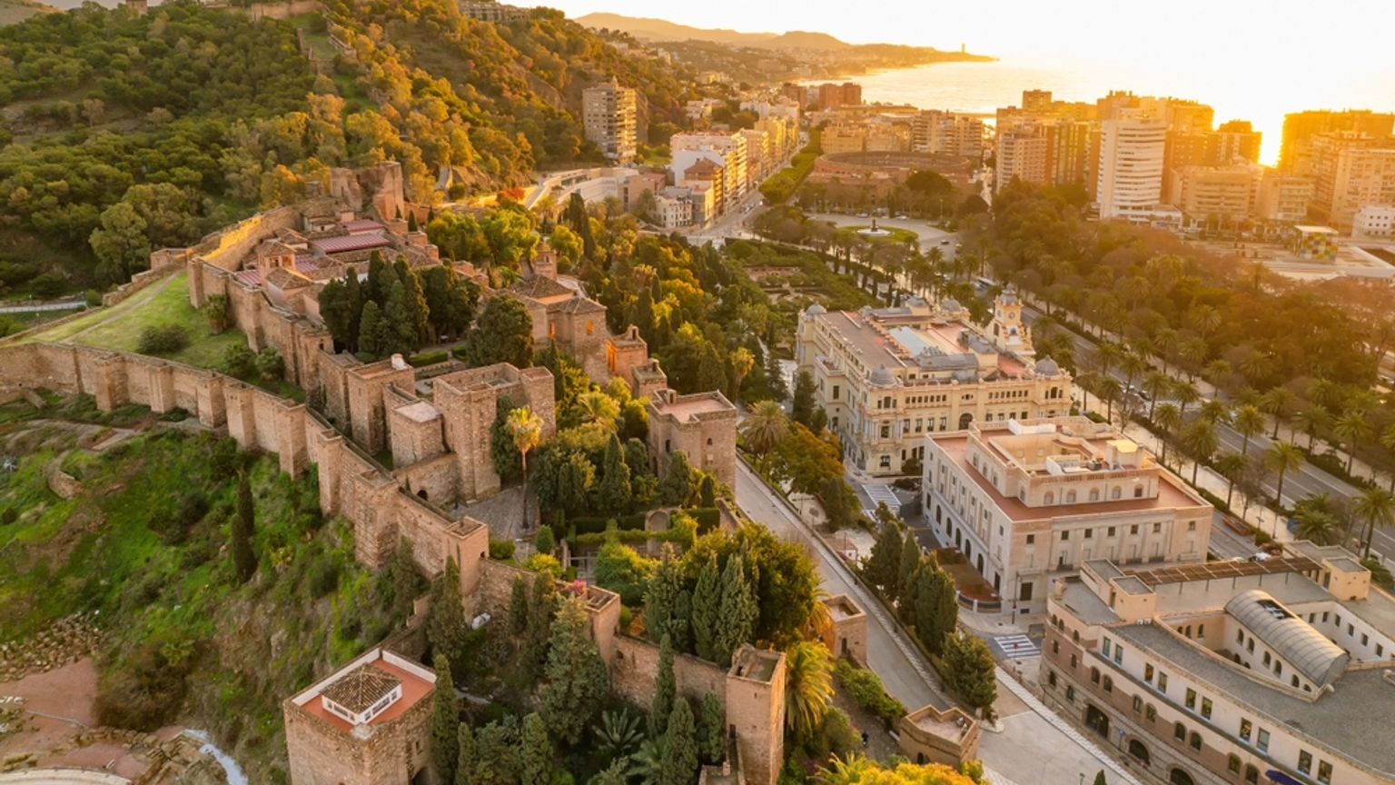 Flygfoto över Alcazaba-fästningen i Málaga med utsikt över staden och bukten vid solnedgången.
