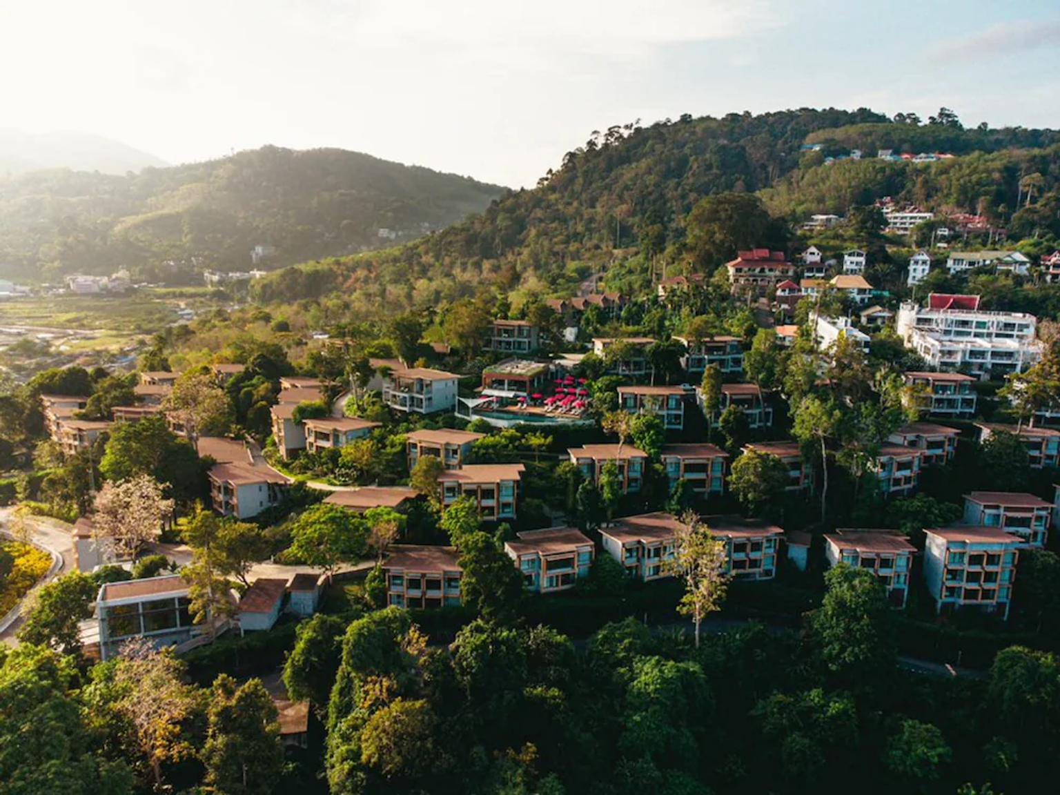 et luftfoto af et boligområde på toppen af en bakke omgivet af træer og bygninger.