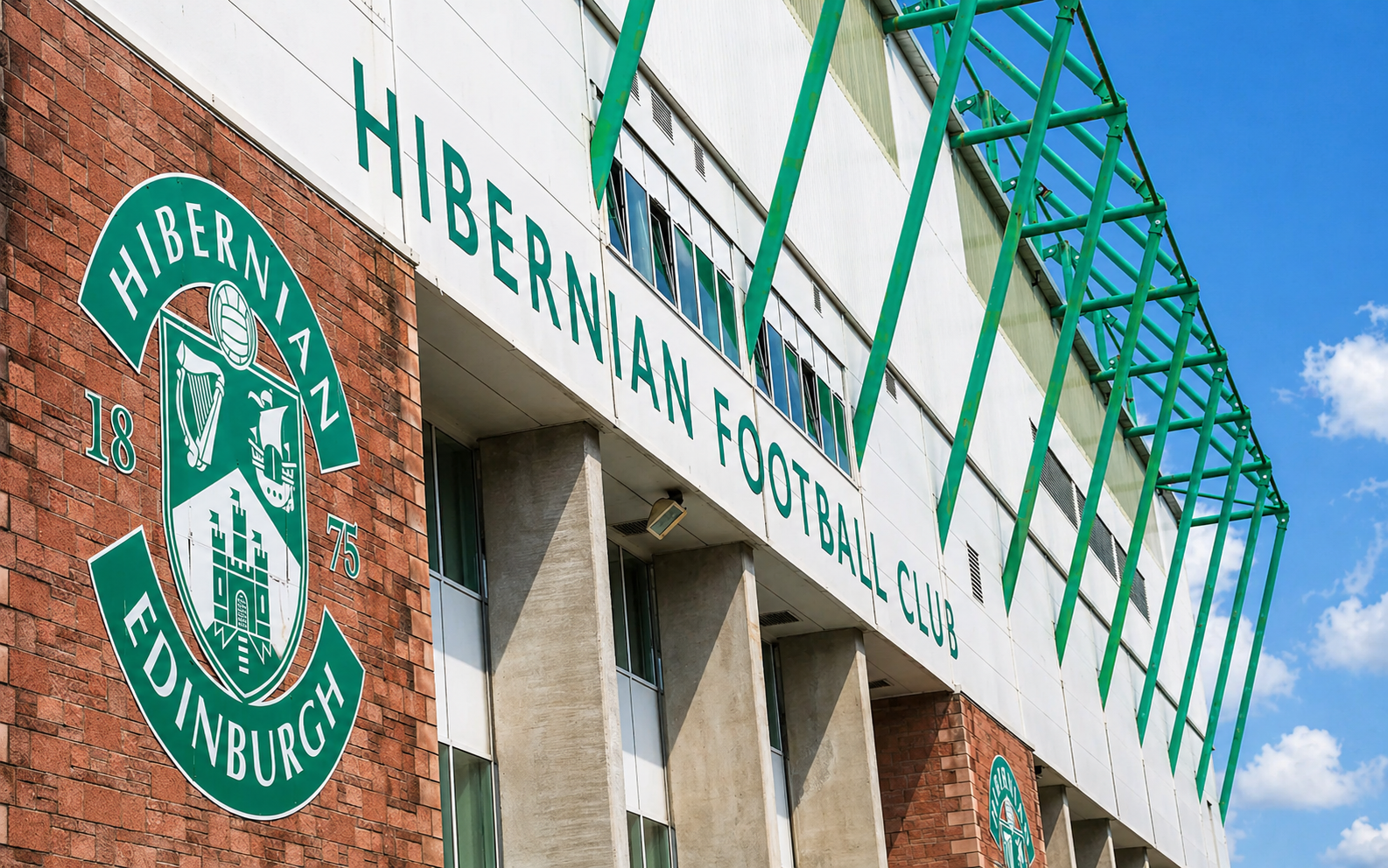Exterior of Hibernian Football Club stadium with its green and white logo and signage.