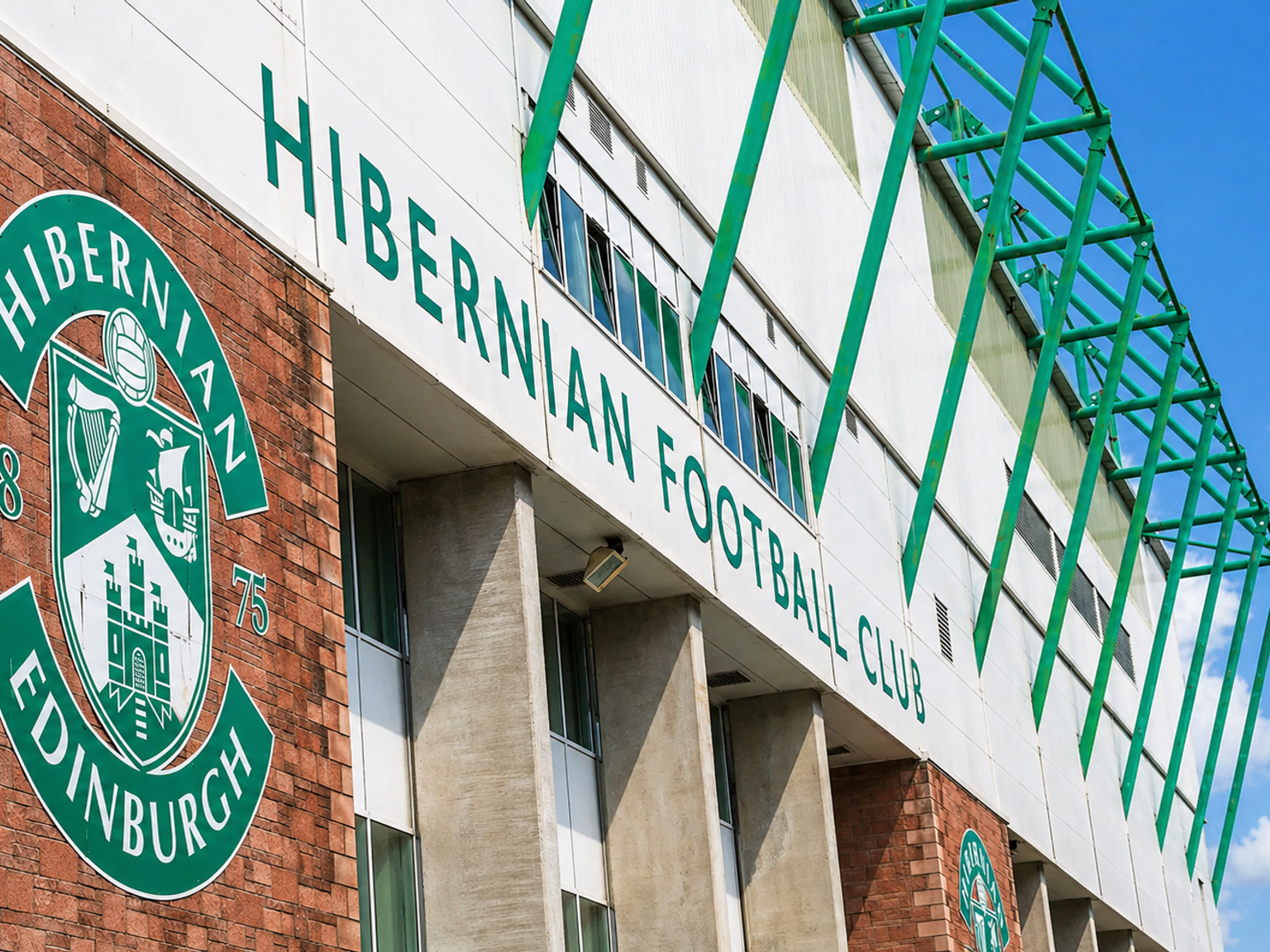 Exterior of Hibernian Football Club stadium with its green and white logo and signage.