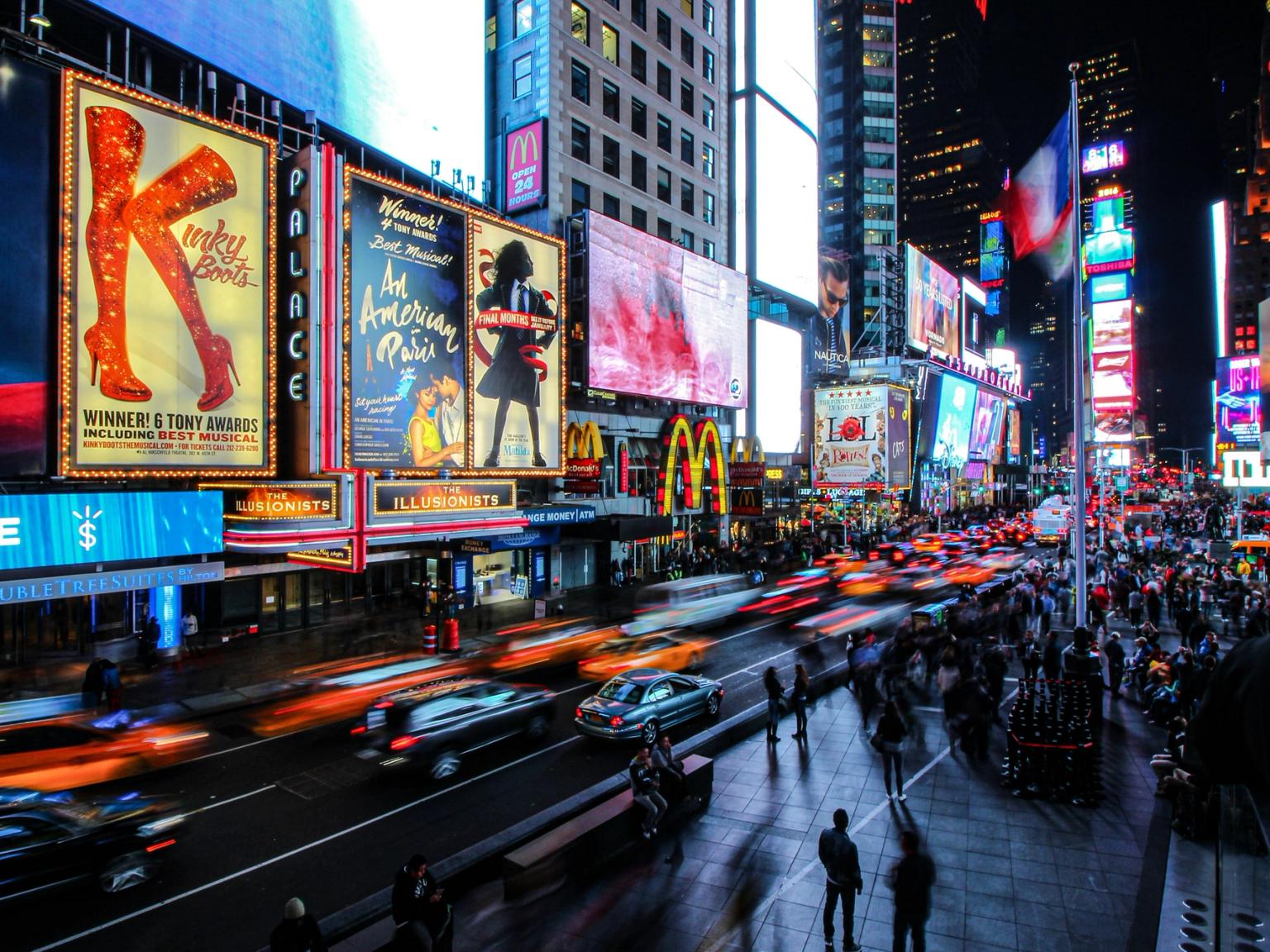 a busy city street at night with a lot of advertisements on the buildings