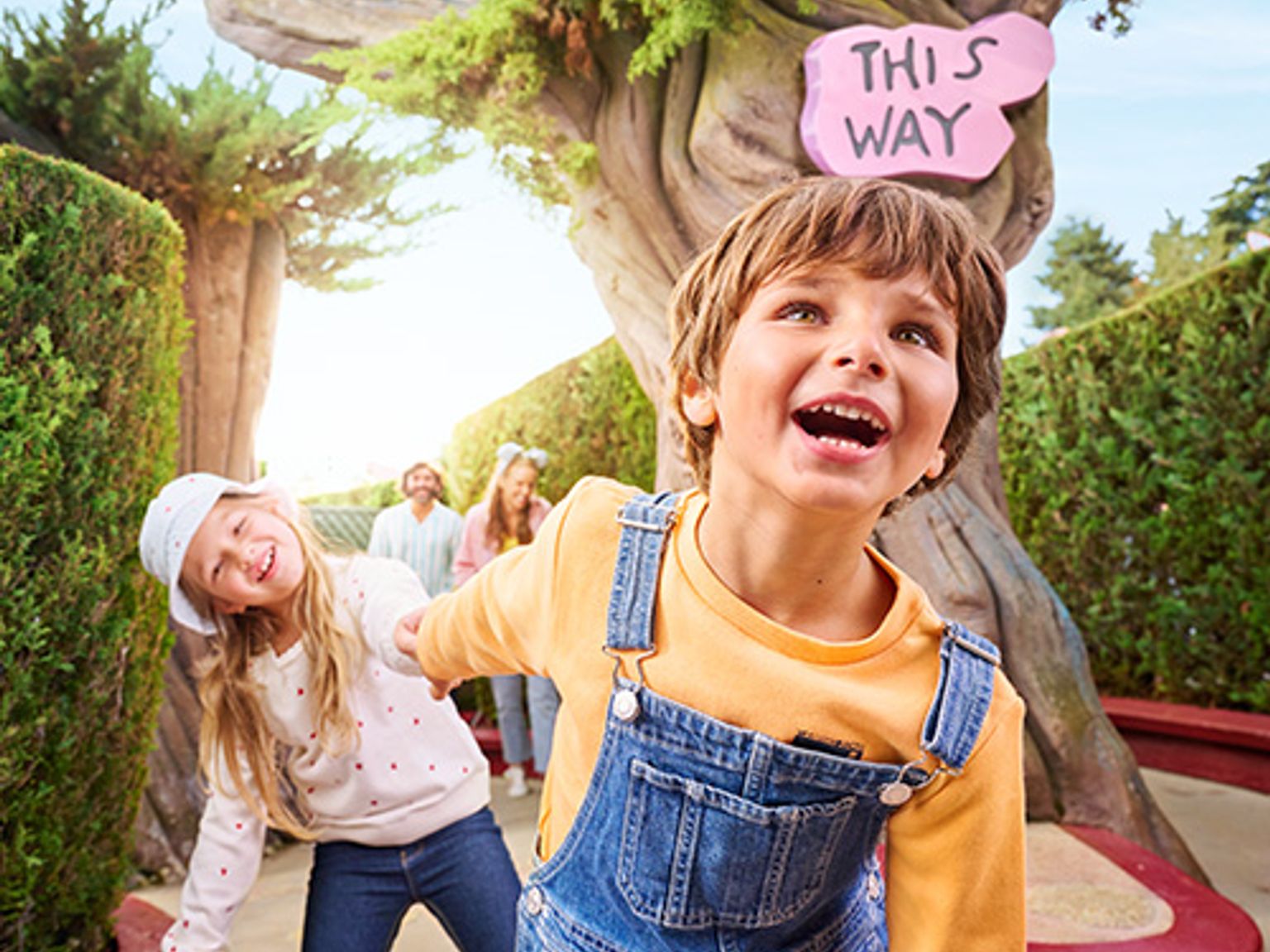 en gutt og en jente står foran et tre med et skilt som sier 'denne veien'