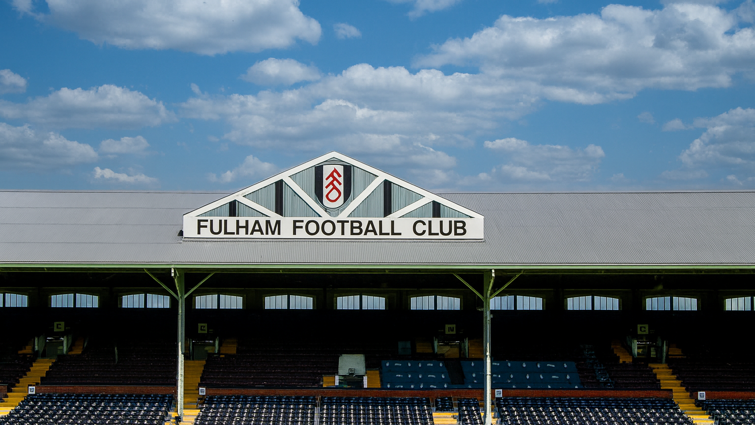 Fulham Football Club stadium stand and empty seats under a blue sky.