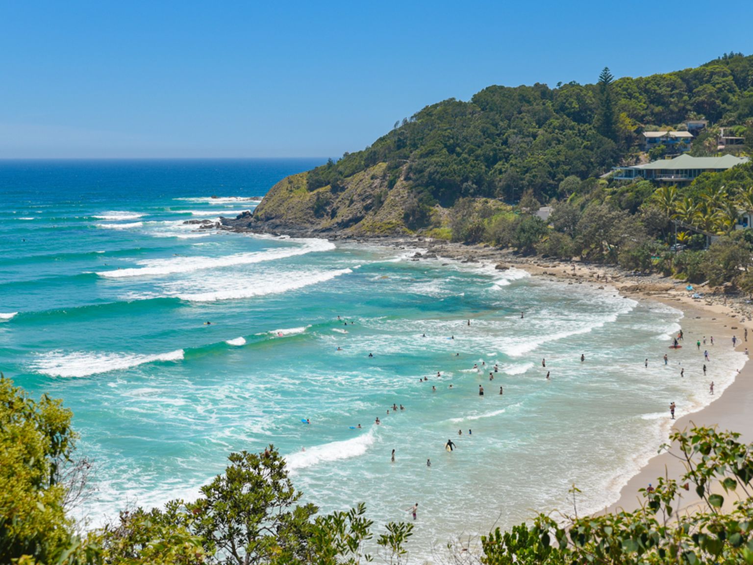 a beach filled with people and waves on a sunny day