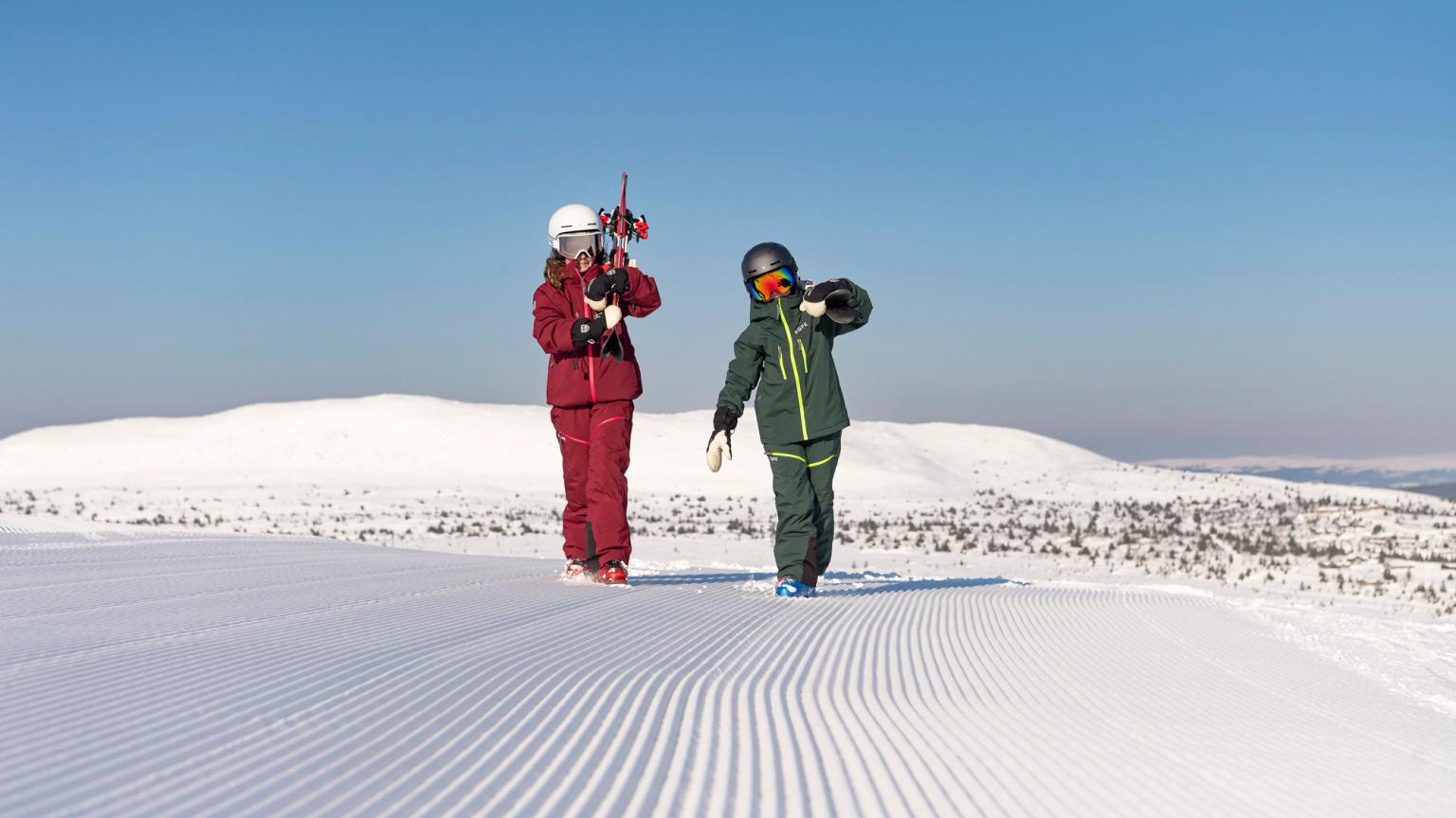 to personer står på toppen av en snødekket bakke