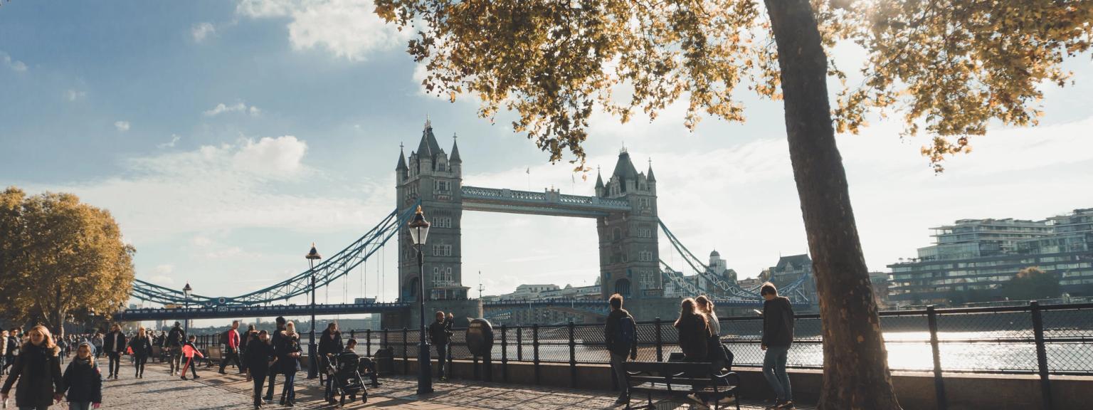 en grupp människor går längs en kullerstensgång framför tower bridge i london