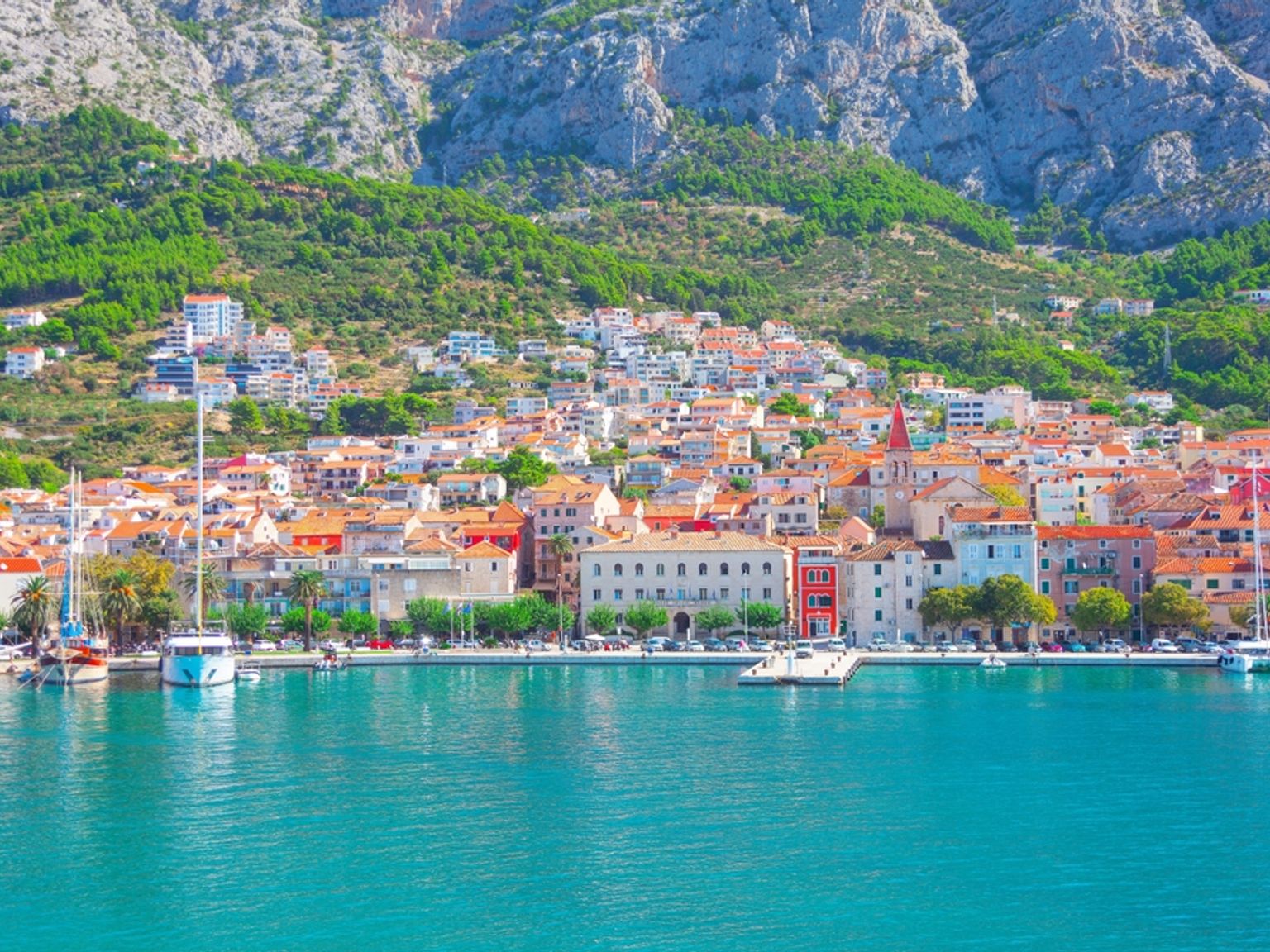 Kystby med fargerike bygninger, en havn og et grønt fjell. Byen Makarska