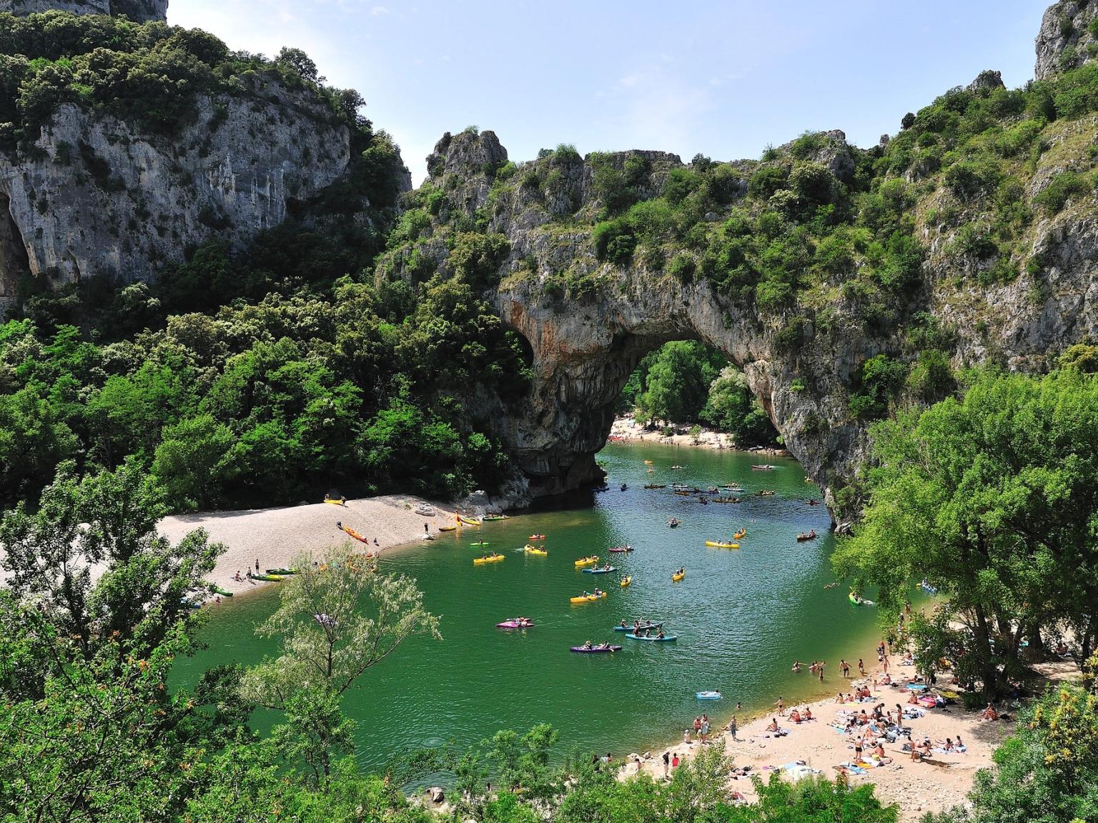 a group of people are swimming in a lake surrounded by mountains.