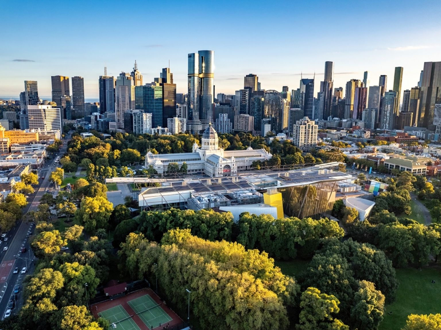 en flygvy över en stadssilhuett med en tennisbana i förgrunden, Melbourne