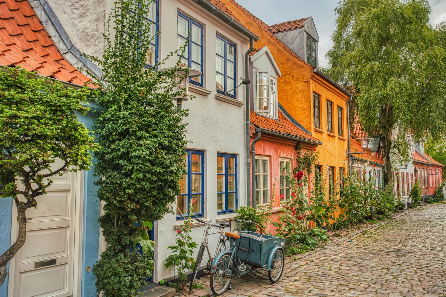 en cykel är parkerad framför en rad färgglada hus på en kullerstensgata