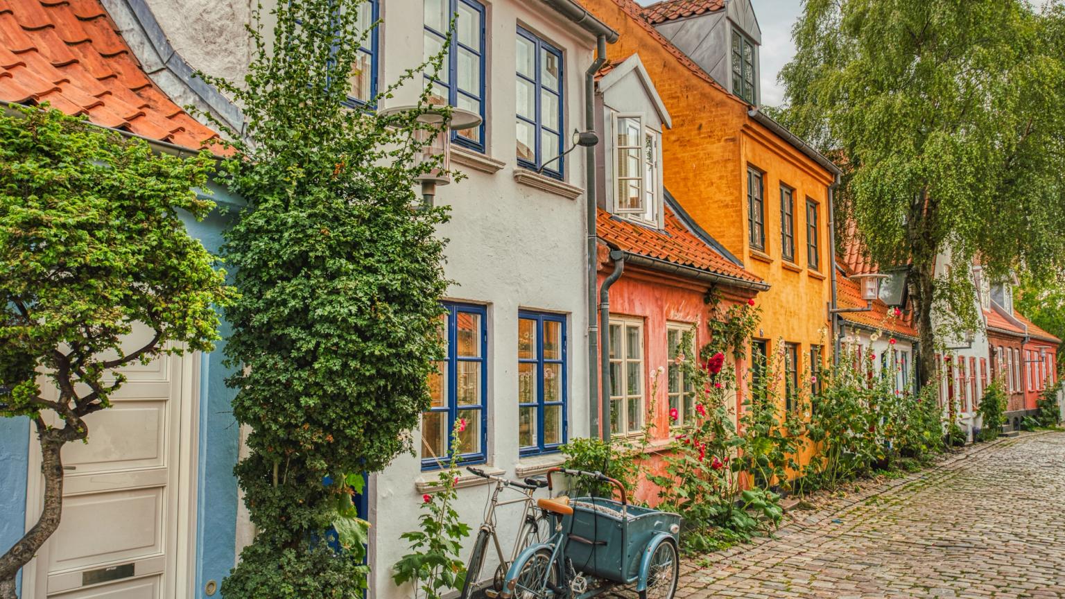 en cykel är parkerad framför en rad färgglada hus på en kullerstensgata