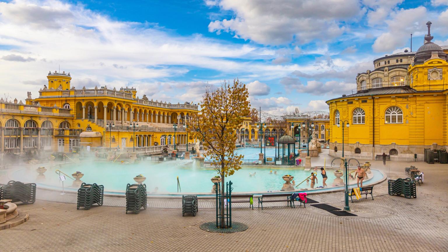 en grupp människor simmar i en stor pool framför en byggnad i Budapest.