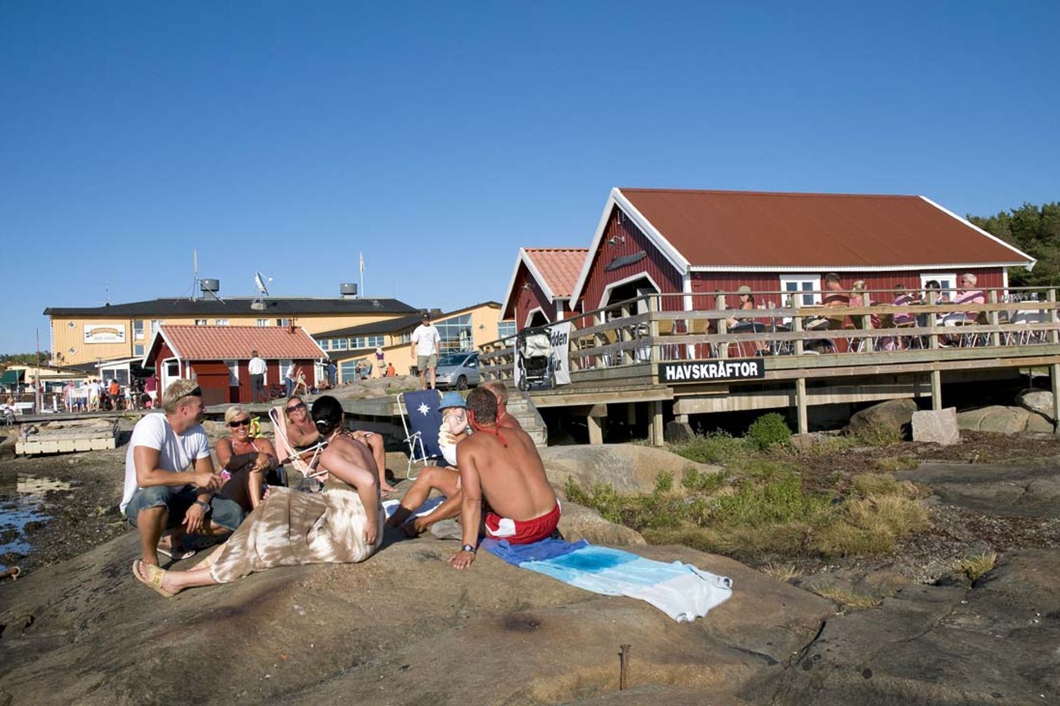 en gruppe mennesker sidder på en klippe på stranden