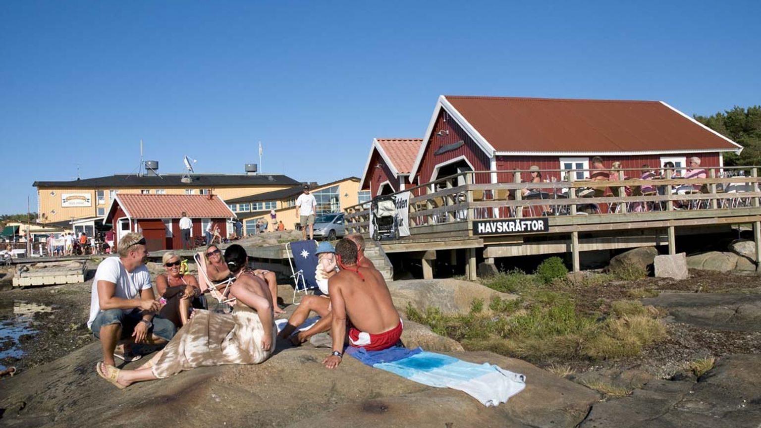 en gruppe mennesker sidder på en klippe på stranden