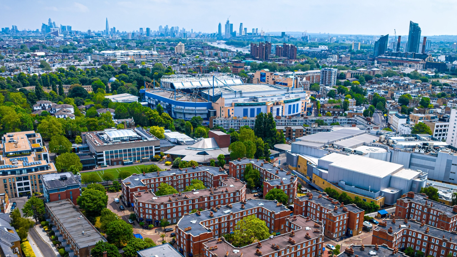 Aerial view of London showing Stamford Bridge stadium, residential areas, and the distant city skyline.