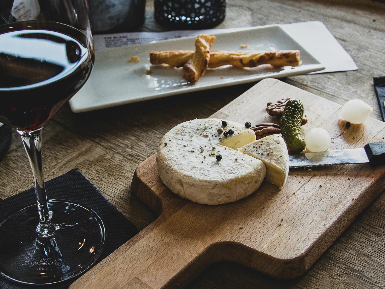 en tre skjærebrett toppet med et stykke ost og et glass vin