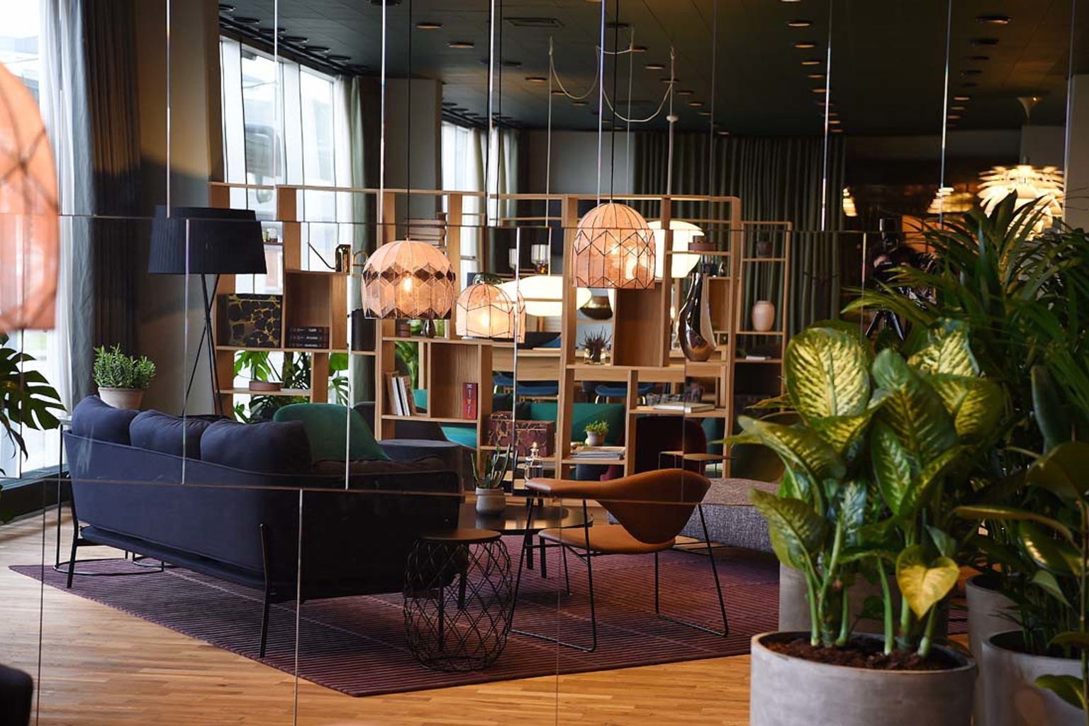 ett vardagsrum med en soffa, stolar, bord och krukväxter.