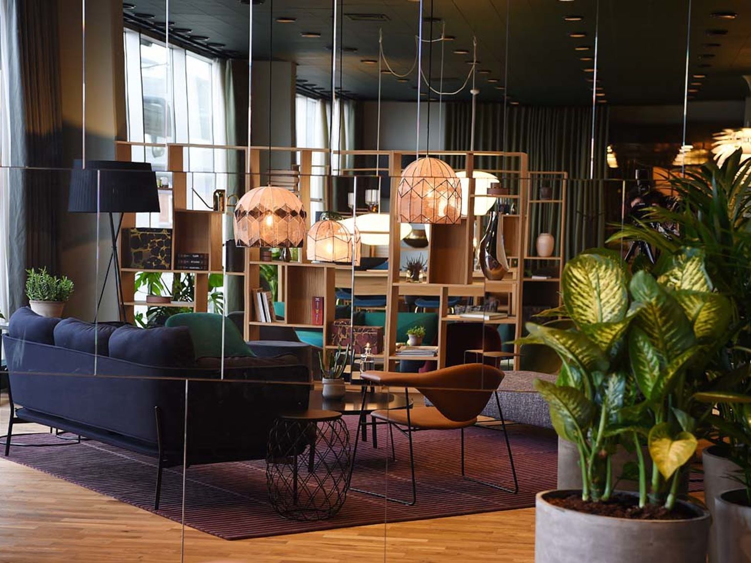 en stue med en sofa, stole, borde og potteplanter.