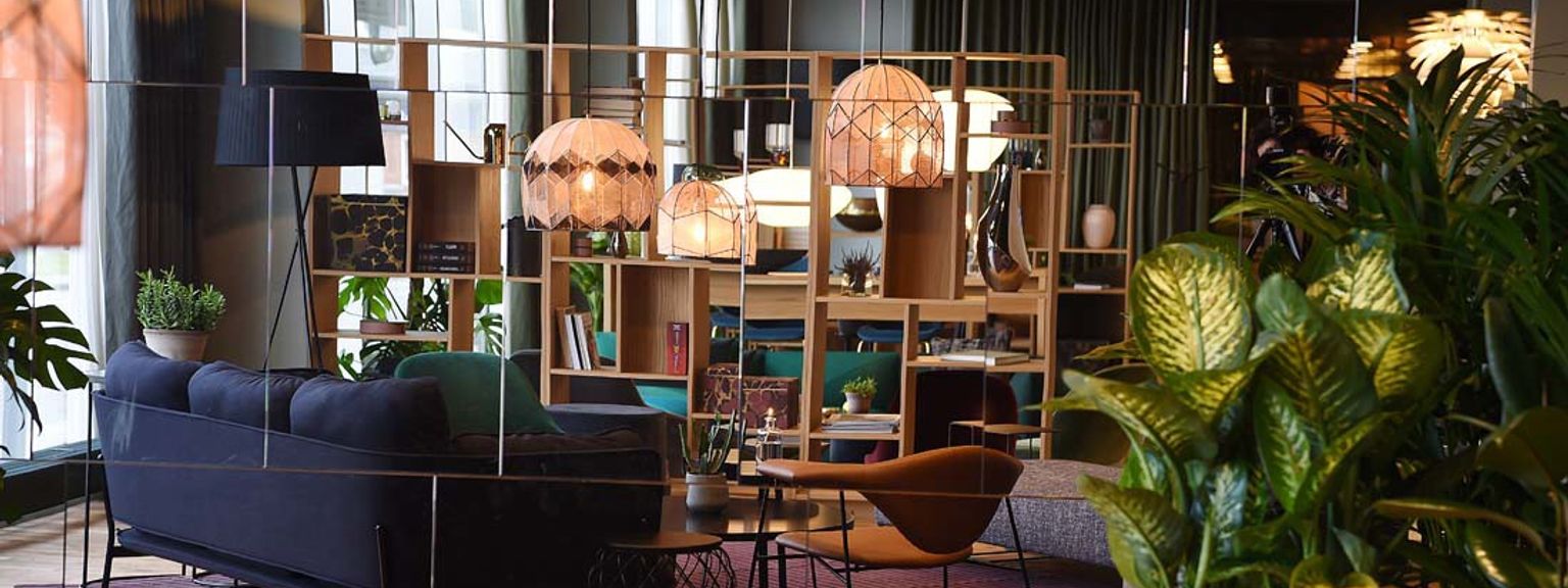 en stue med en sofa, stole, borde og potteplanter.