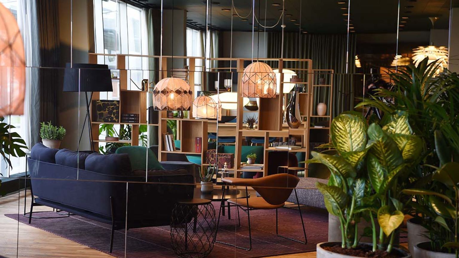 ett vardagsrum med en soffa, stolar, bord och krukväxter.