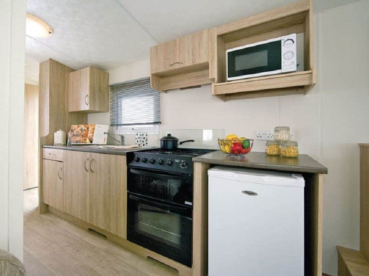 a kitchen with a stove, microwave, refrigerator and sink.