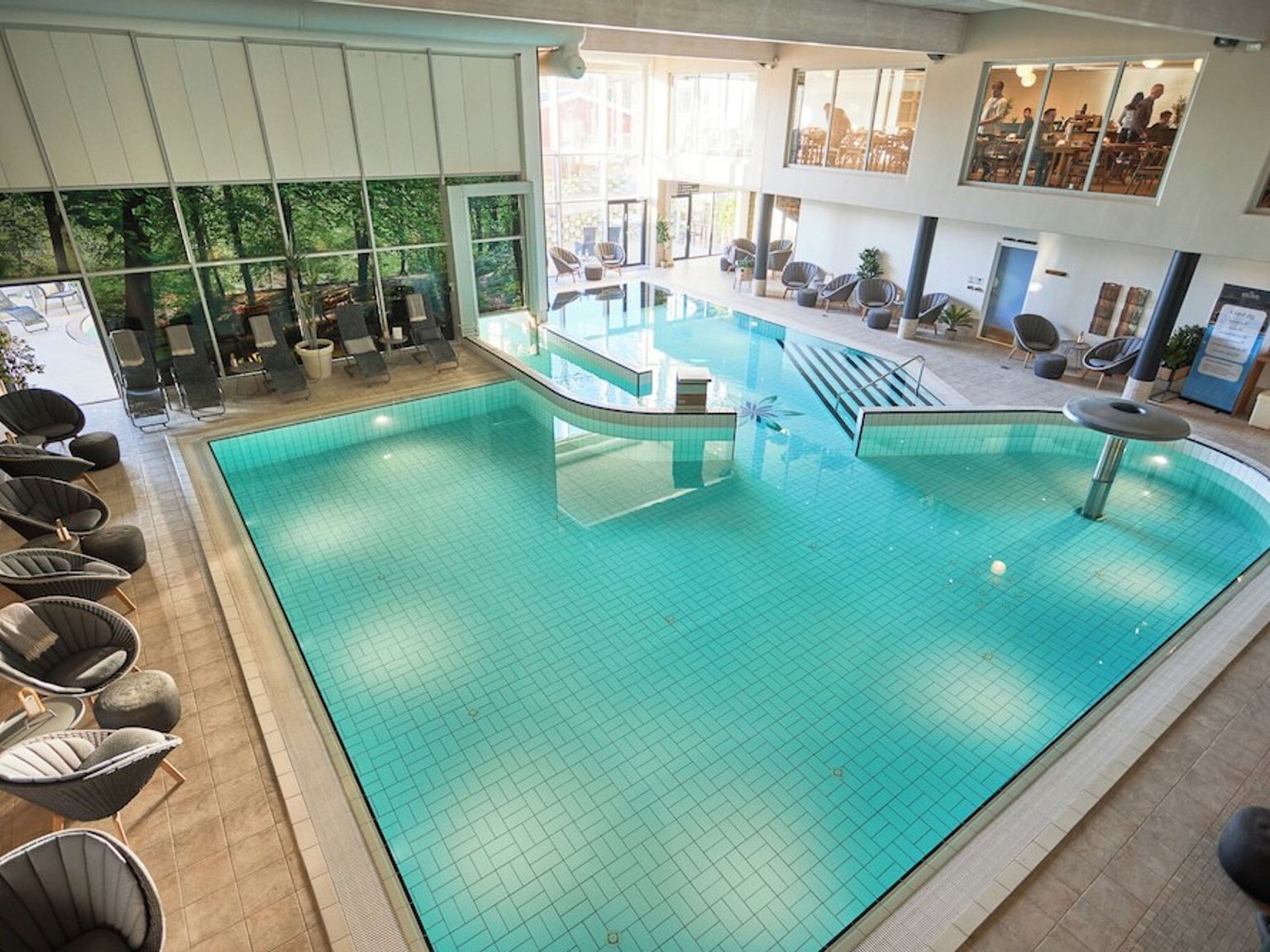 et stort innendørs svømmebasseng omgitt av stoler og bord