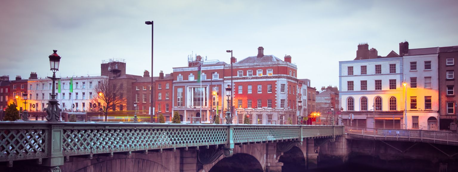 en bro över en flod i en stad med byggnader i bakgrunden, Dublin