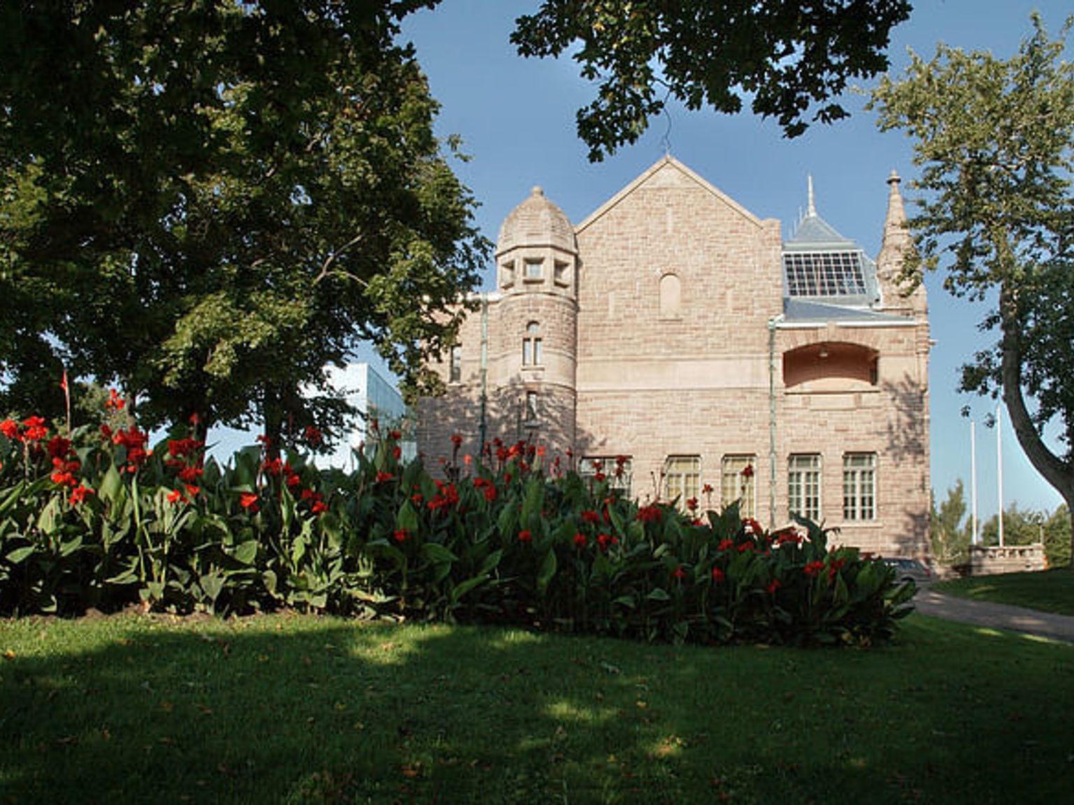 a large brick building with a tower on top of it is surrounded by trees and flowers.