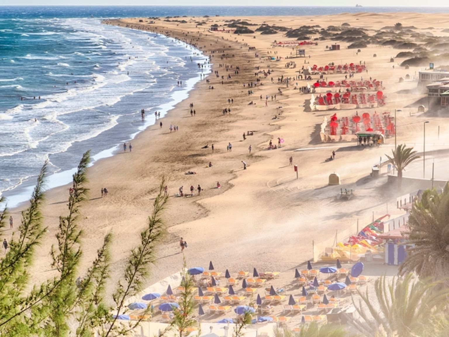 en strand med många människor och parasoller
