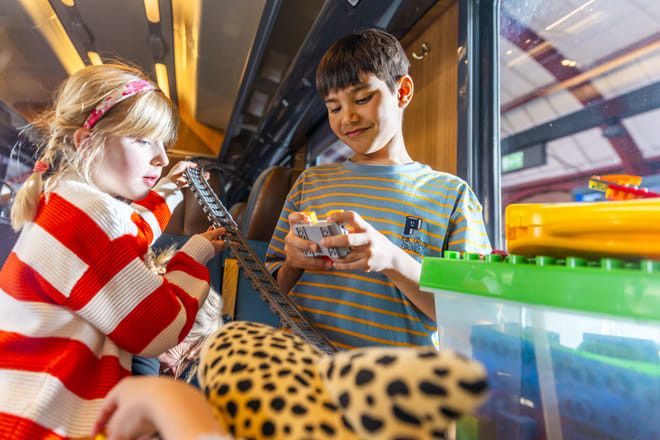 Barn leker med tågräls och byggklossar.