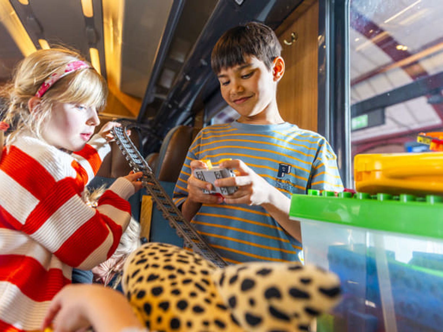 Barn leker med tågräls och byggklossar.