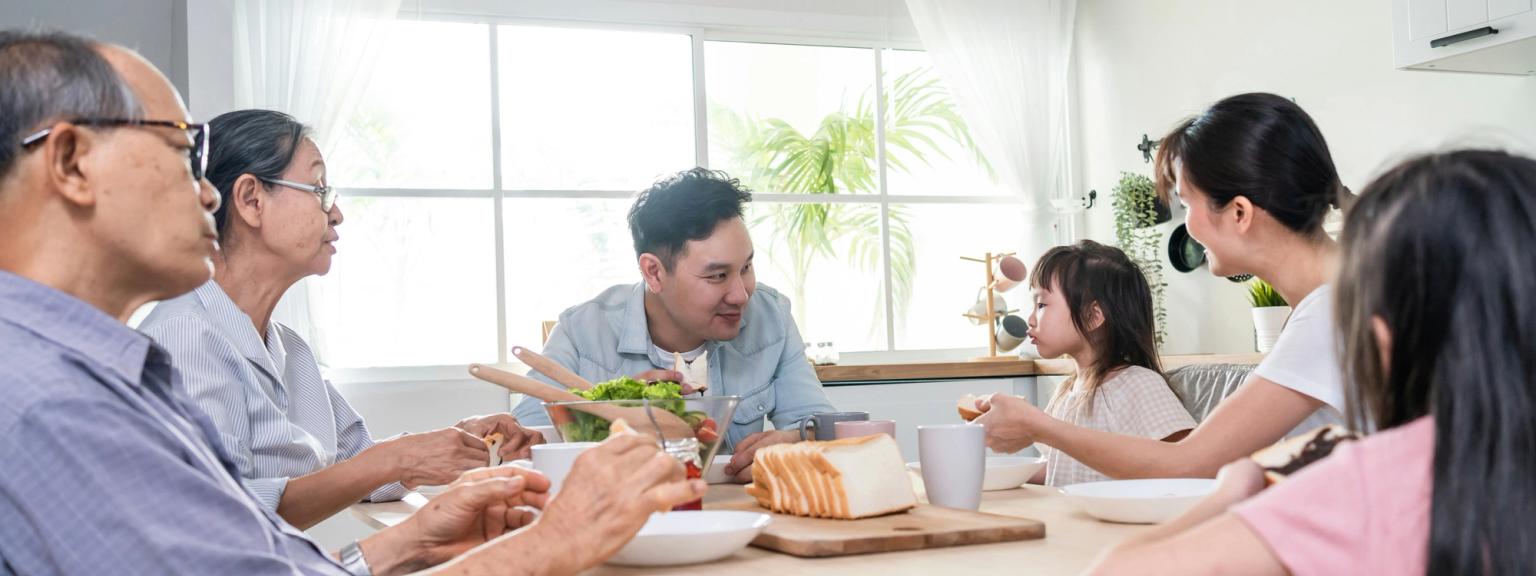 en familj sitter vid ett bord och äter mat tillsammans