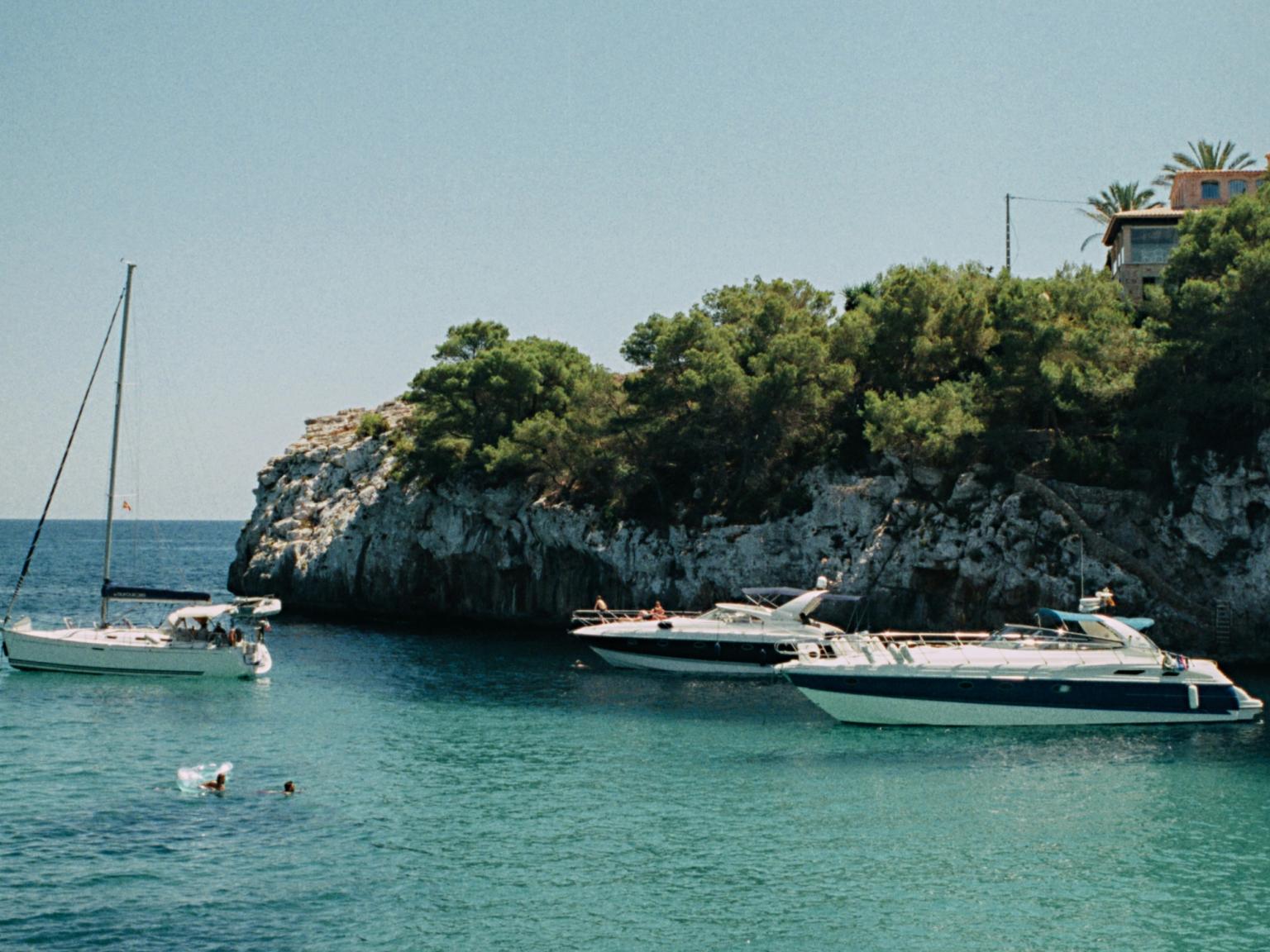 ett par bÄtar Àr i vattnet nÀra en klippa