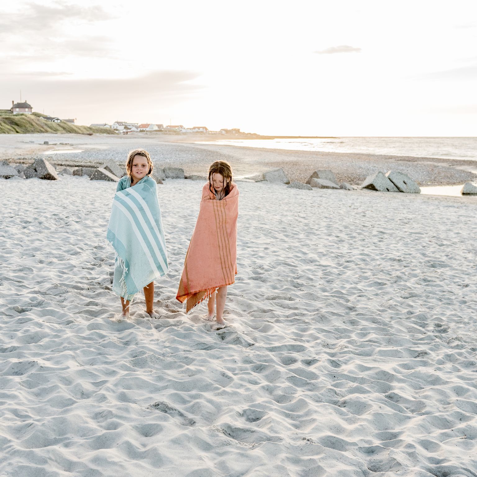 to piger indpakket i håndklæder går på stranden