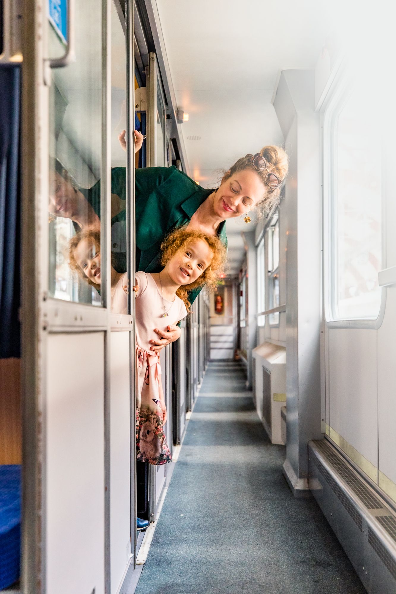 Leende kvinna och barn som tittar ut från ett tågfack.