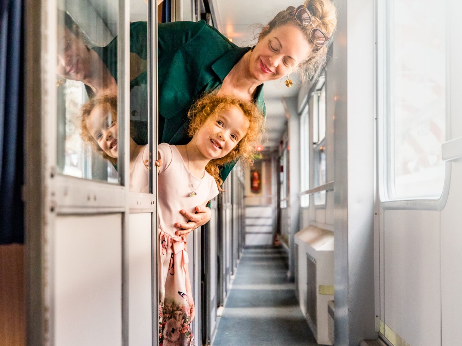 Leende kvinna och barn som tittar ut från ett tågfack.