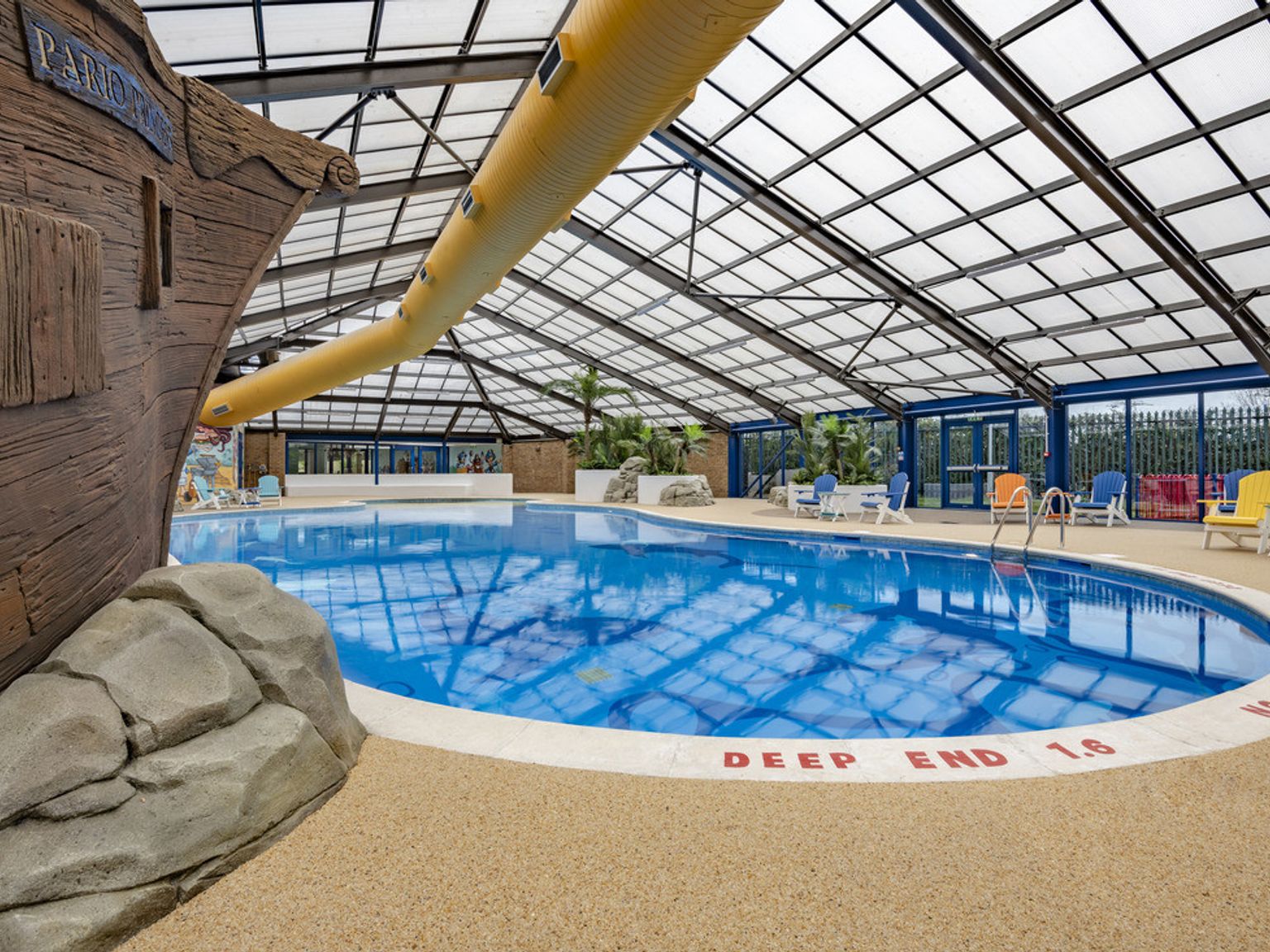 a large indoor swimming pool with a pirate ship in the background