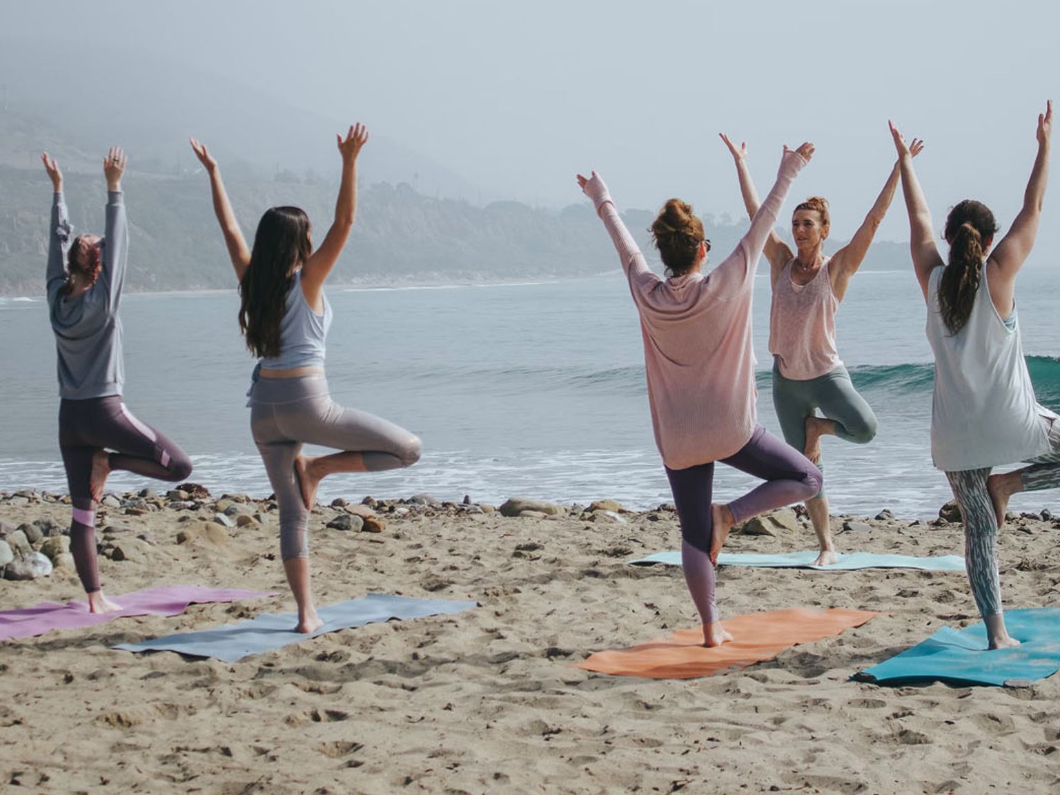en grupp kvinnor övar yoga på stranden