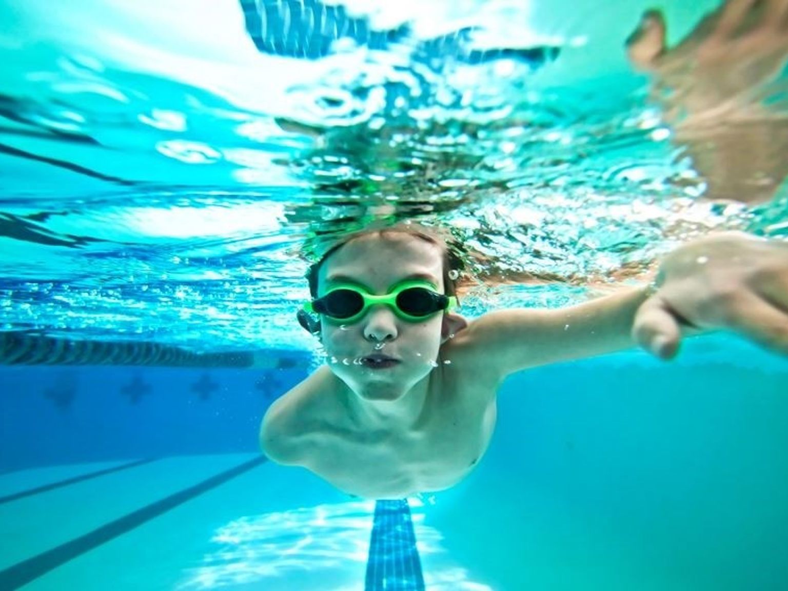 a young child is swimming underwater in a swimming pool.