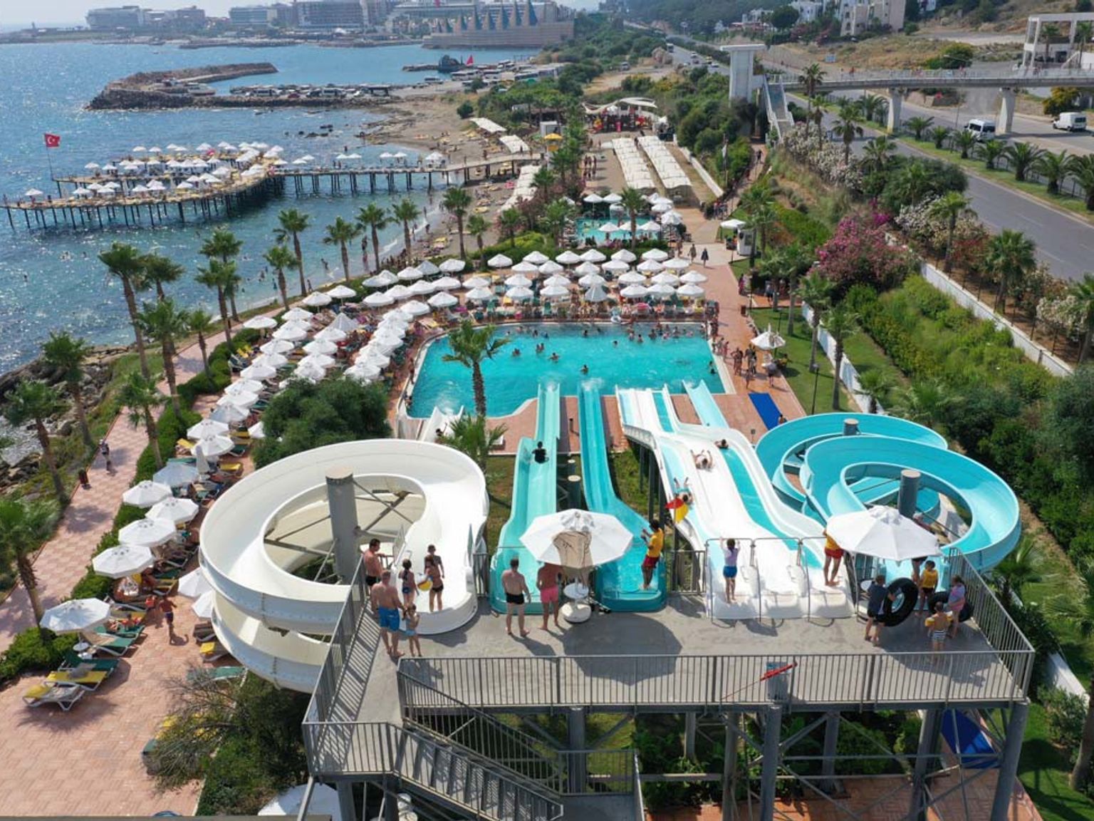Luftfoto af en livlig vandland og resortstrand fyldt med mennesker ved siden af havet. Vikingen Infinity Resort og Spa, Alanay
