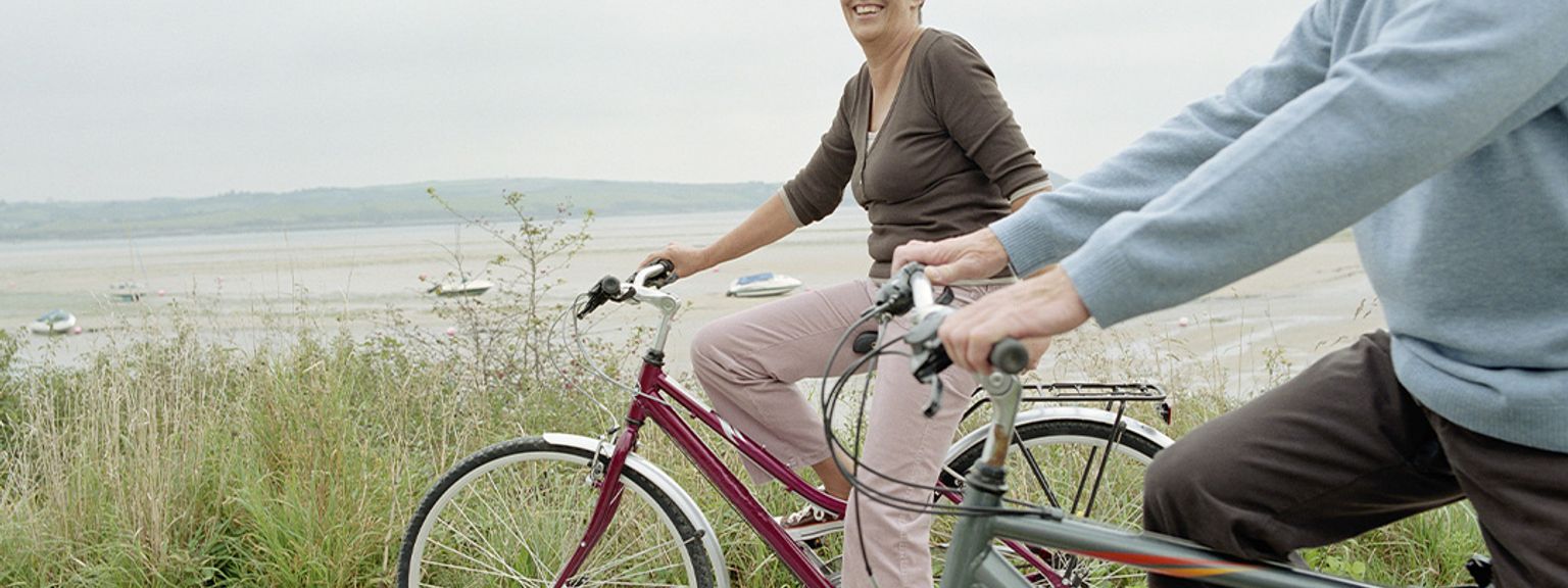 ein Mann und eine Frau fahren mit dem Fahrrad eine Straße hinunter