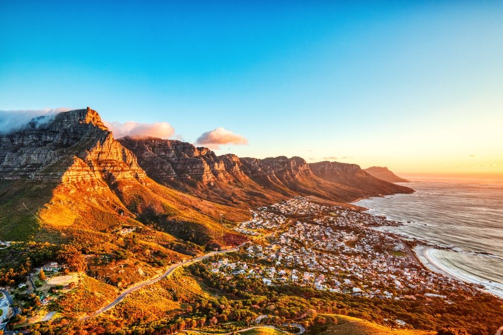 Taffelbjerget og en kystby ved havet ved solnedgang.
