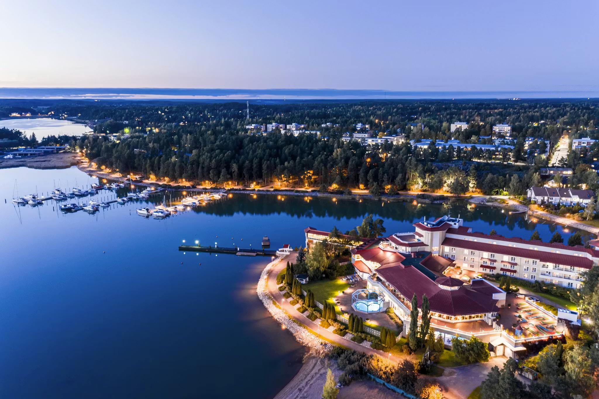 Aerial view of an illuminated lakeside resort and marina at twilight.