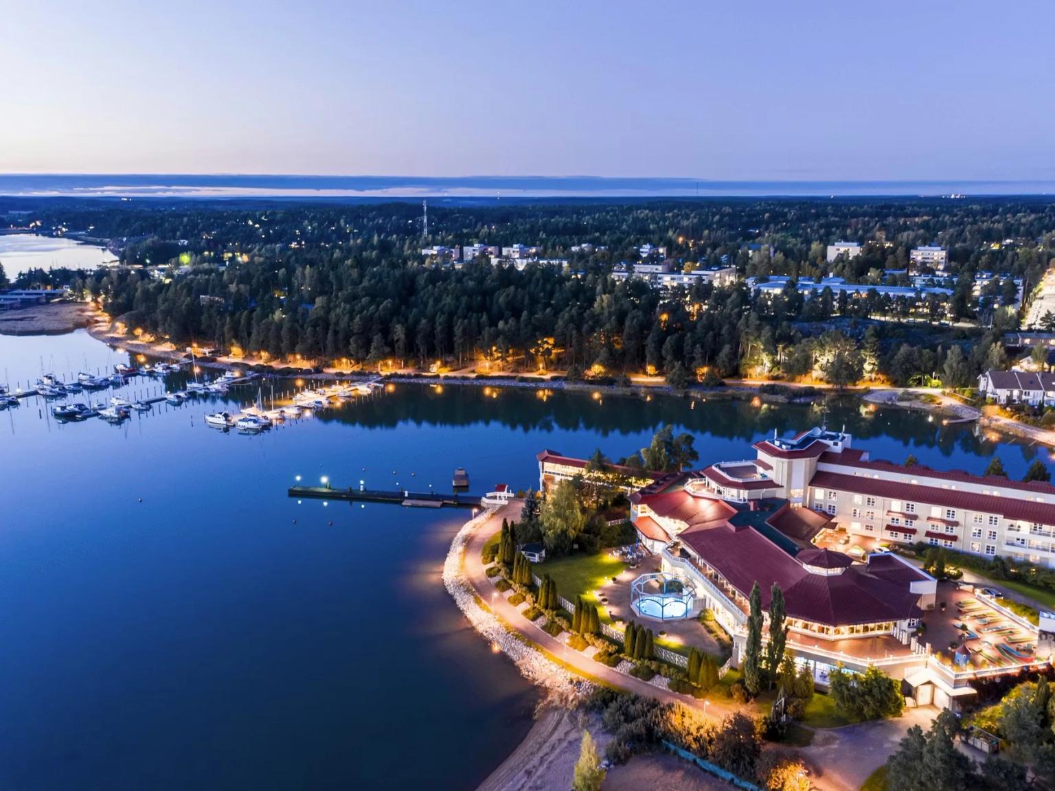 Aerial view of an illuminated lakeside resort and marina at twilight.