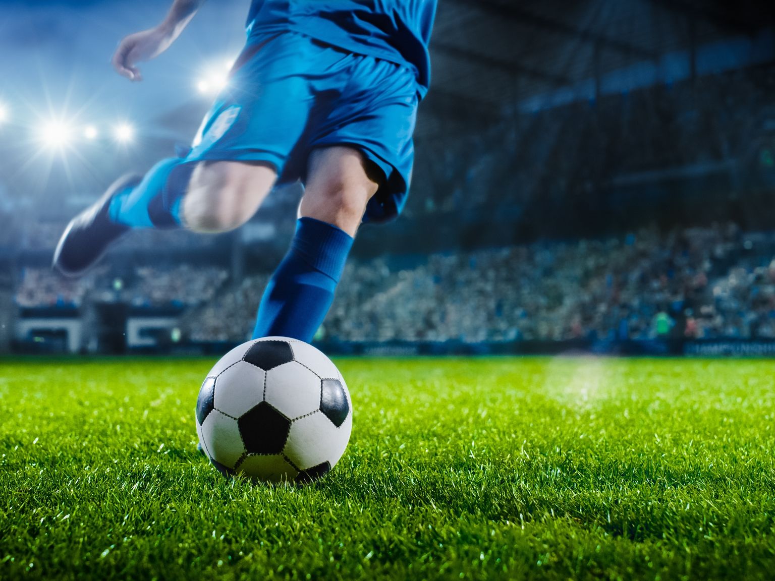en fotballspiller sparker en fotball på en bane