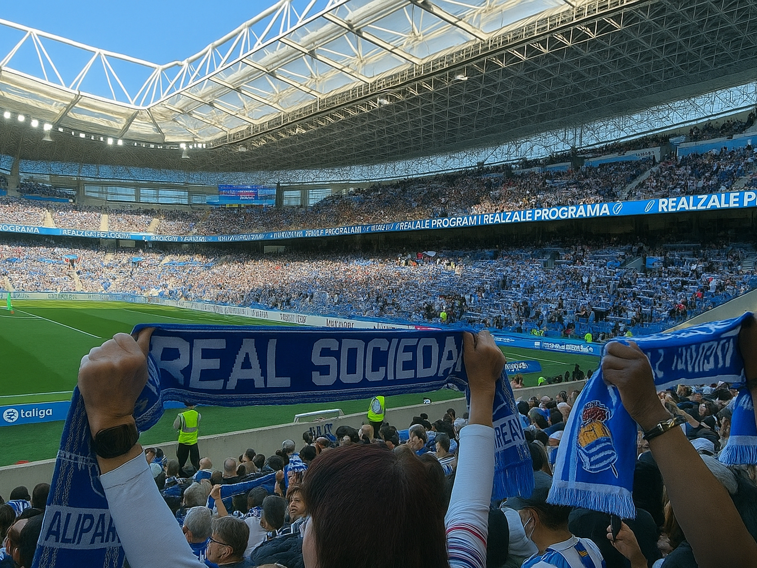 Überfülltes Fußballstadion mit Fans, die Real Sociedad-Schals hochhalten.