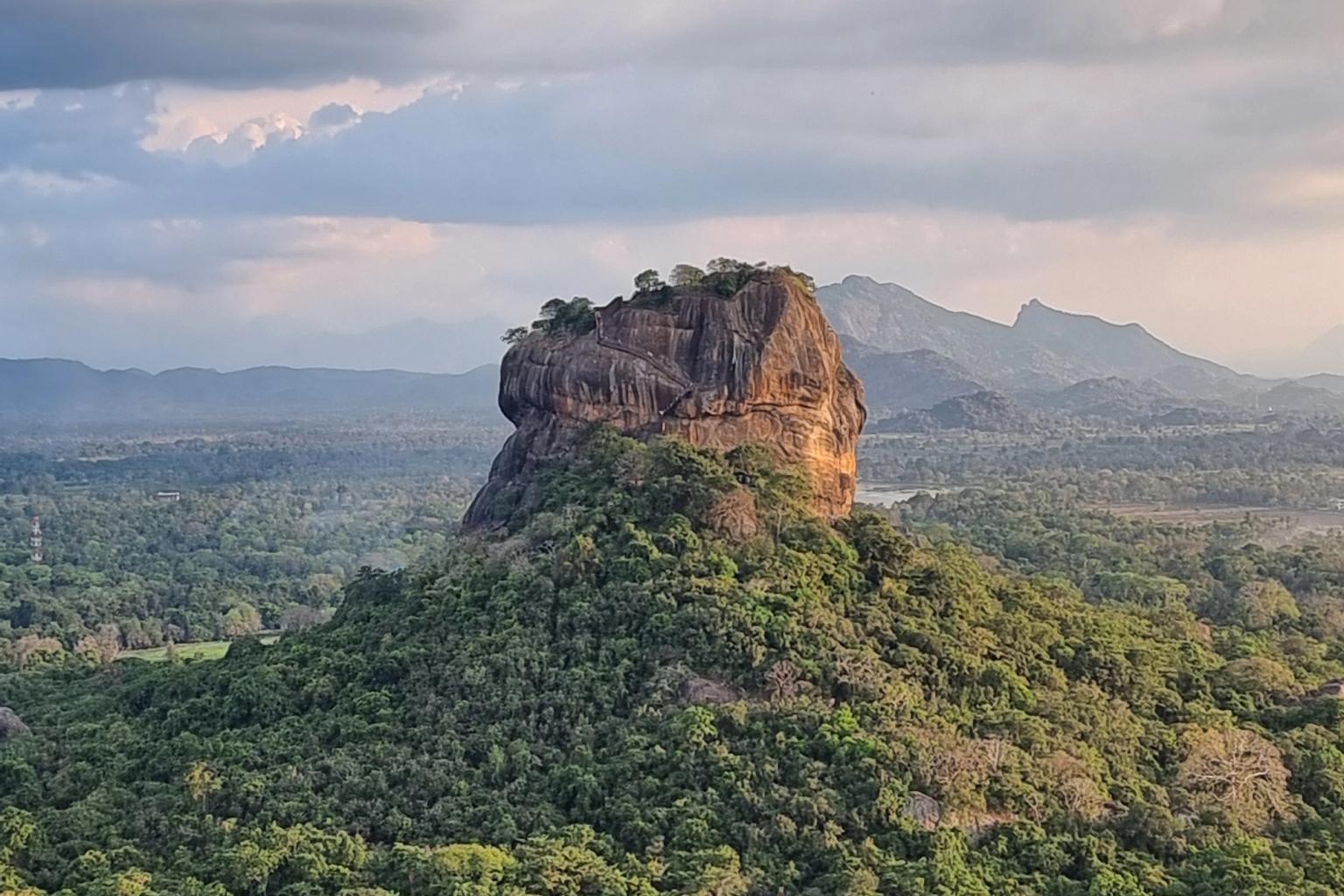 en stor sten mitt i en skog med berg i bakgrunden