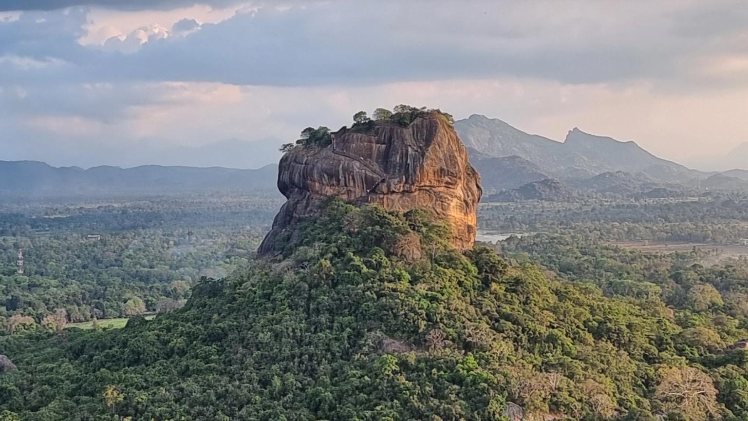 en stor sten mitt i en skog med berg i bakgrunden