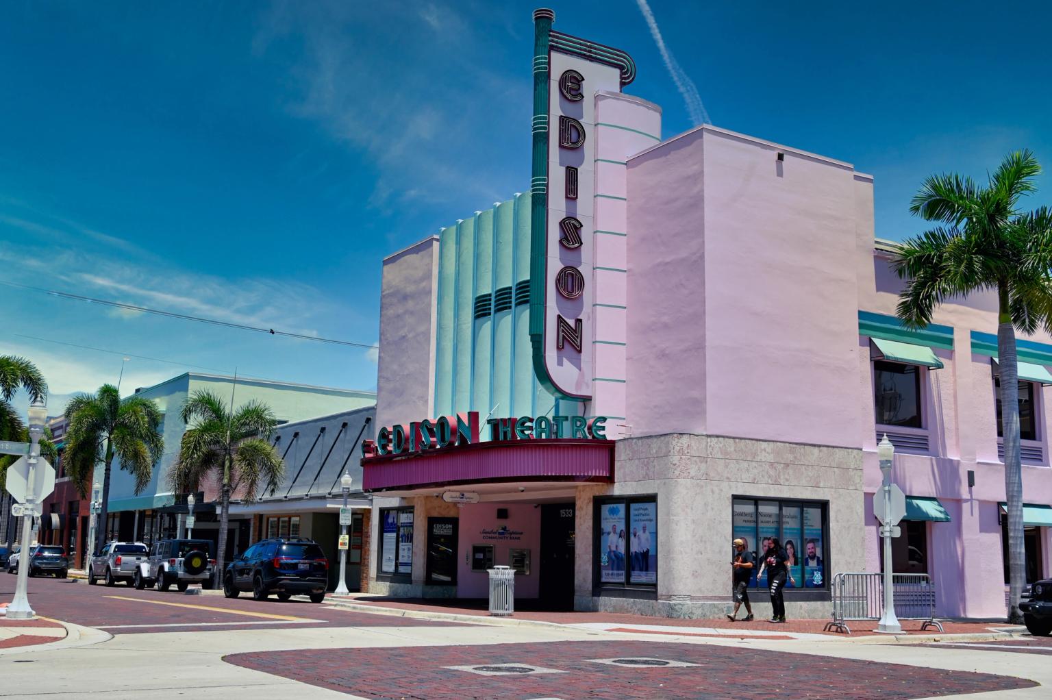 en rosa og grønn bygning med et skilt på den er på hjørnet av en bygate.